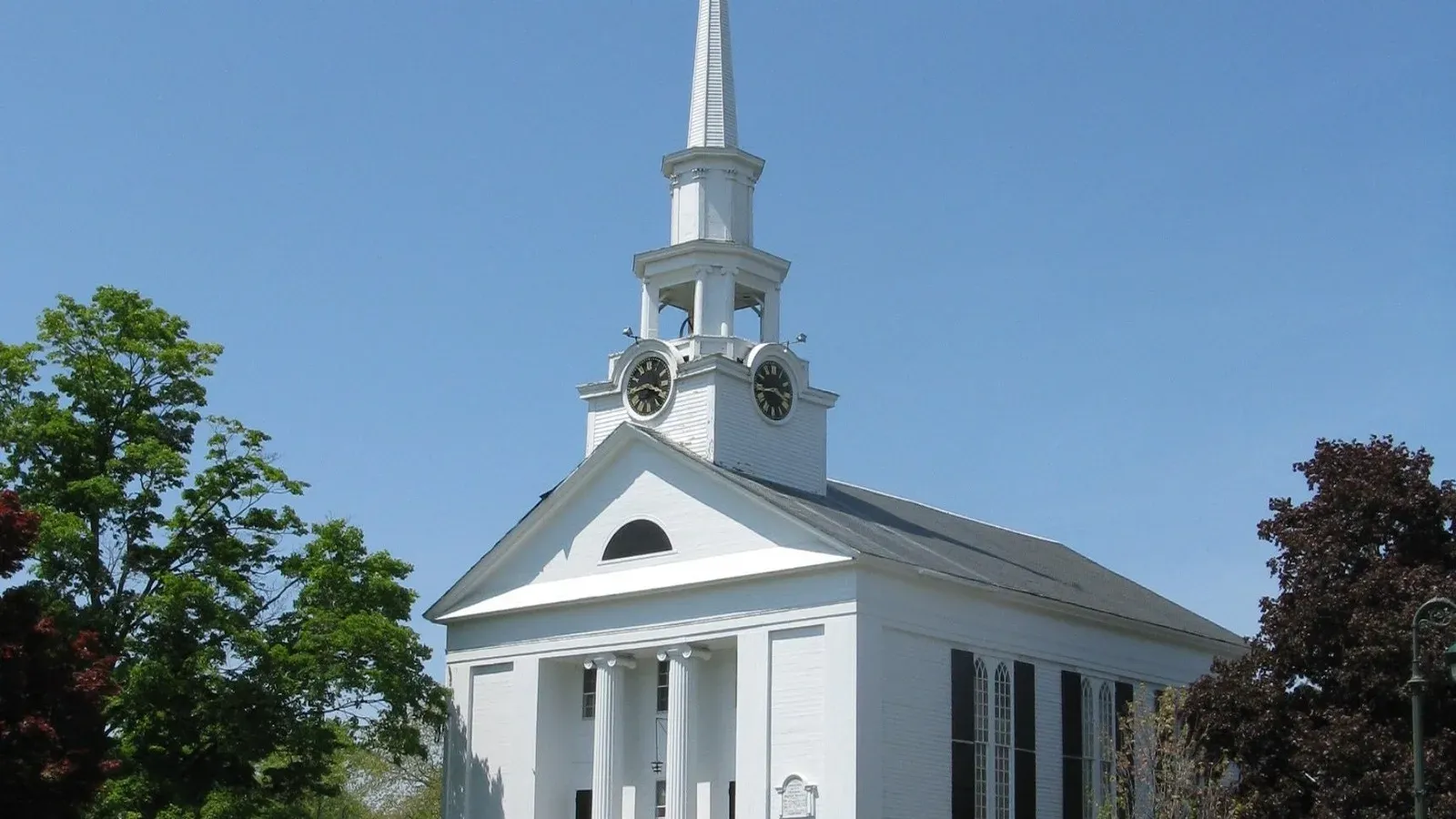 White Greek Revival church with a columned portico and tall steeple on the town common, Chelmsford, Massachusetts